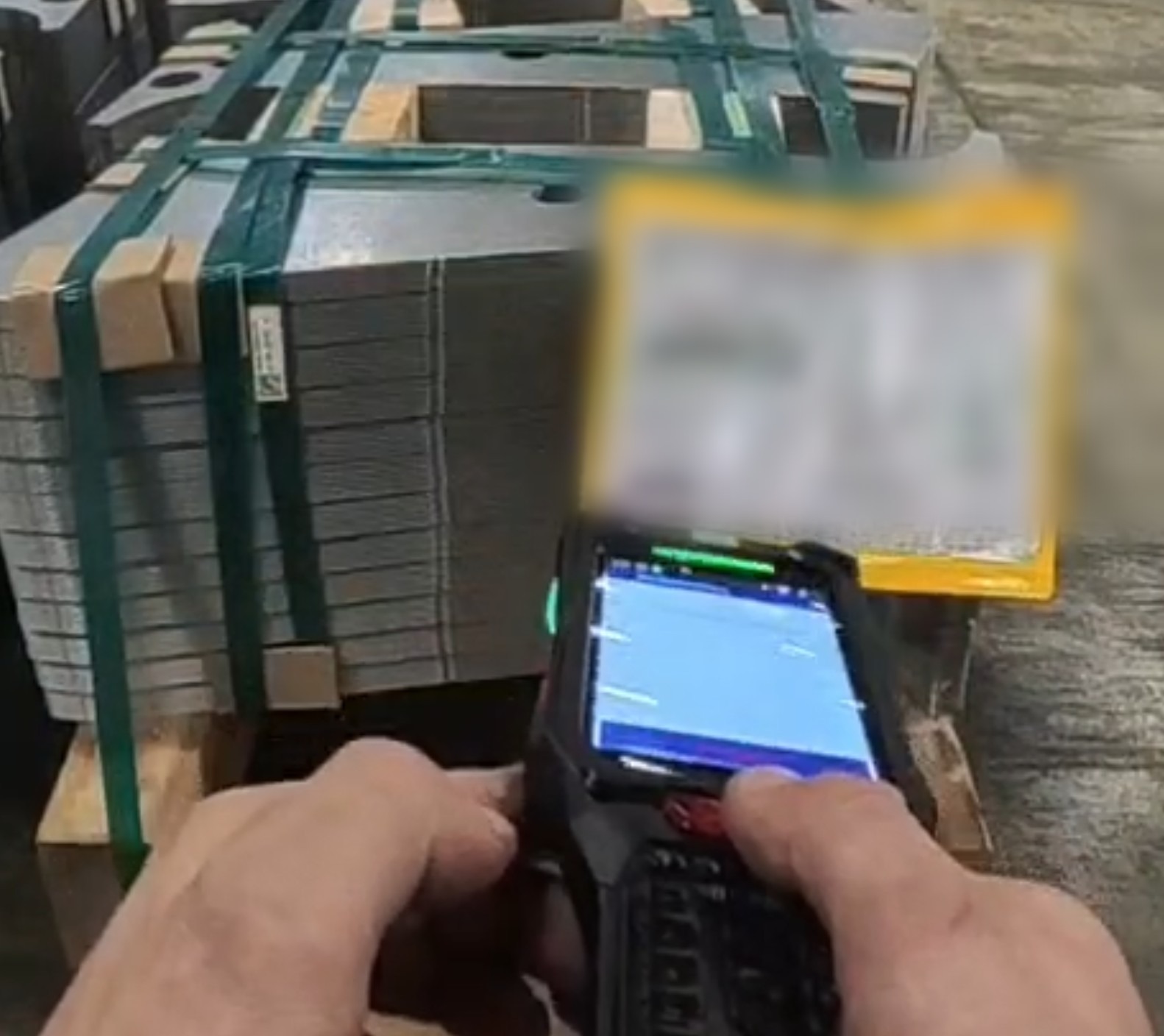 Mitarbeiter scannt bei der Kommissionierung im Warenausgang eine Palette Metallplatinen mit einem mobilen Keyence-Handheld