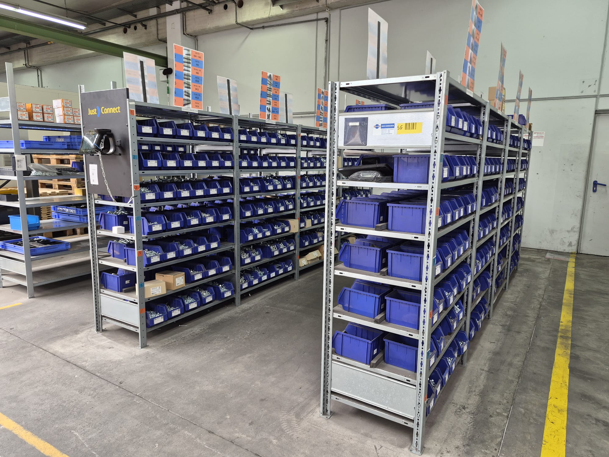 C-Teile-Regal mit blauen Kanban-Behältern und Just-Connect-Station im Lager des Industriekunden